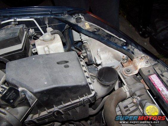 Close-up of a car's engine bay showing the air filter box, hoses, and radiator