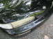 1995 Nissan 240SX - Close-up of a black car's front corner, showing the Nissan badge and headlight assembly.