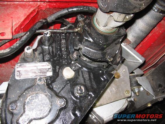Close-up of a vehicle's steering box and driveshaft assembly, with a metal data plate visible