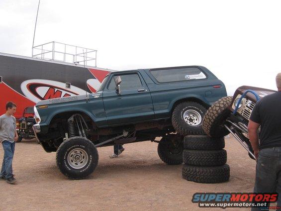 Green 1978 Ford Bronco lifted on tires, with another vehicle partially visible on the right