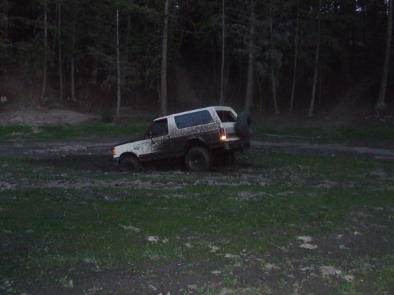1990 Ford Bronco stuck in mud, rear-mounted spare tire visible