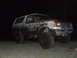 1990 Ford Bronco - This heavily mud-splattered SUV is viewed from the front-right at night.
