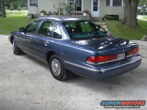1996 Ford Crown Victoria, rear 3/4 view, blue paint, parked on gravel driveway