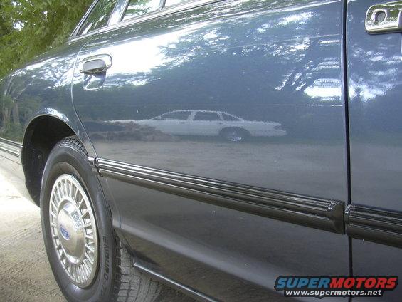 Blue 1996 Ford Crown Victoria side view, showing reflection of another white car