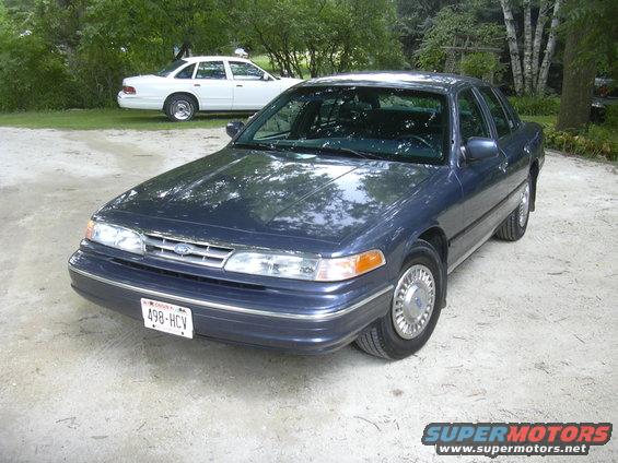 Dark blue 1996 Ford Crown Victoria parked on gravel, white Ford Crown Victoria in background