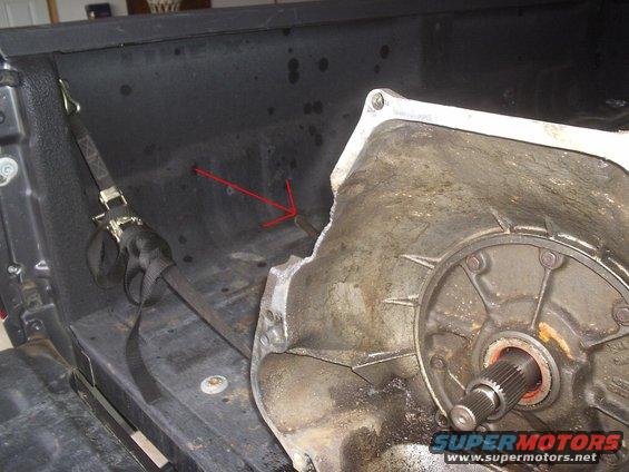 Cracked transmission housing in truck bed with red arrow pointing to damage