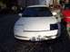 1993 Ford Probe - A white 1993 Ford Probe is parked in front of a red car and a wooden structure.