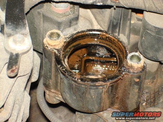 close-up of open engine component with rusty fluid inside