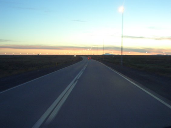 Road stretching into the distance at dusk with a single car visible far ahead
