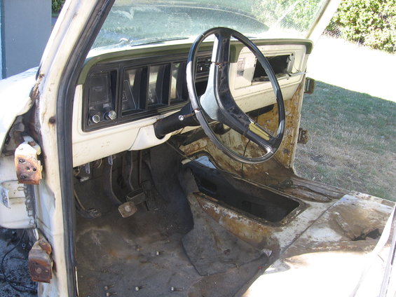 Interior of a rusty 1976 Ford F-150 showing dashboard and steering wheel