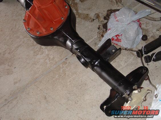 black rear axle assembly with orange differential cover, on concrete floor