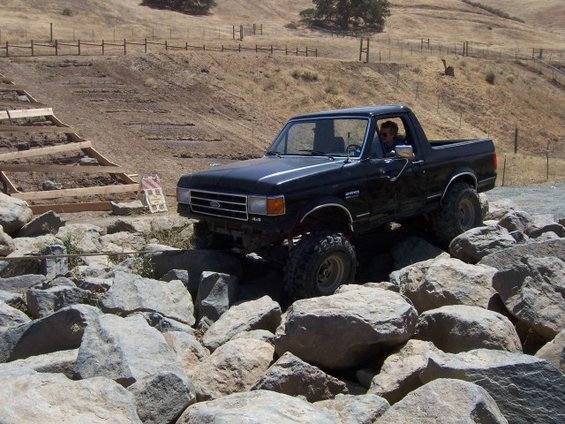 Black Ford Bronco with lifted suspension navigating a rocky terrain