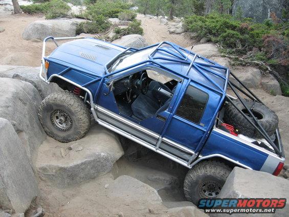 Blue 1997 Chevrolet C/K Pickup modified for off-roading, climbing over rocks
