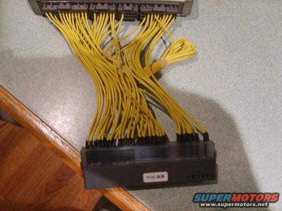 Automotive wiring harness connector with many yellow wires and black connectors. Text 'FC35' is visible