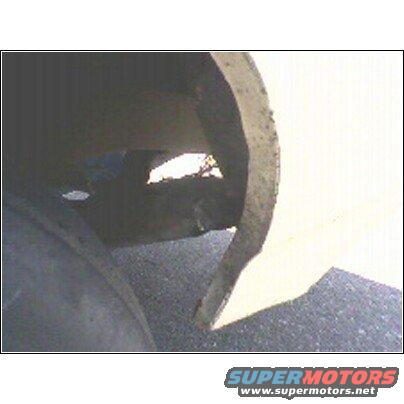 Close-up of a damaged wheel well with a hole showing daylight