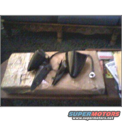Three black car side mirrors on a cardboard box