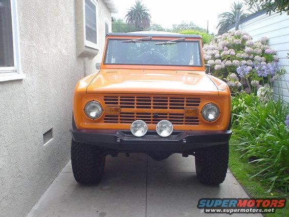 Front view of an orange 1977 Ford Bronco parked in a driveway