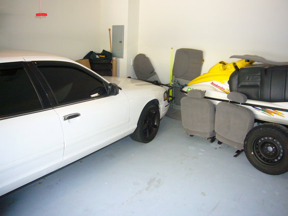White 2000 Ford Crown Victoria parked in a garage next to a jet ski and loose car seats