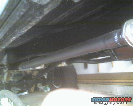 Undercarriage view of a truck showing the exhaust pipe and rear axle. A Supermotors.net watermark is visible