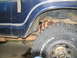 1978 Ford Bronco - The rear wheel well of a blue vehicle is shown, with visible suspension and exhaust system parts.