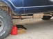 1978 Ford Bronco - A close-up view of a vehicle's undercarriage shows a rusty exhaust system and a tire.