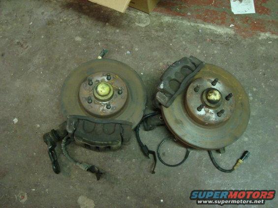 Two front brake rotor and caliper assemblies on a concrete floor