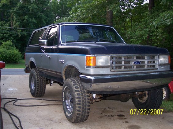 Lifted Ford Bronco with aftermarket wheels and tires. Dark blue and silver two-tone paint