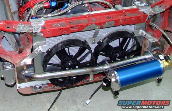 Engine bay with dual electric fans, radiator, and a blue canister. Some red metal framing is visible