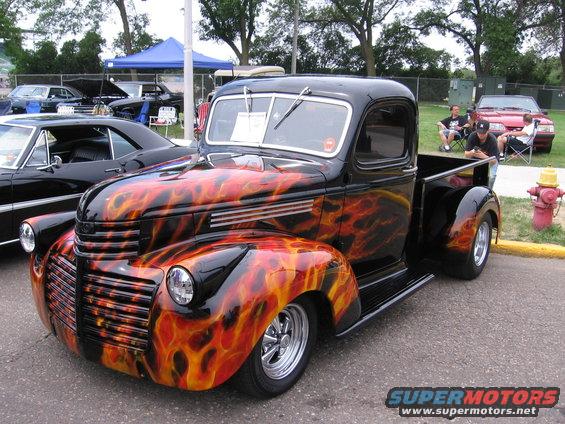 black pickup truck with flame graphics, parked next to a black car and a red car