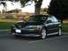 2005 Mazda 6 - A dark gray sedan is parked in a lot with trees and a grassy hill in the background.