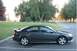2005 Mazda 6 - A dark gray 2005 Mazda 6 sedan is parked in a lot with trees and a road in the background.