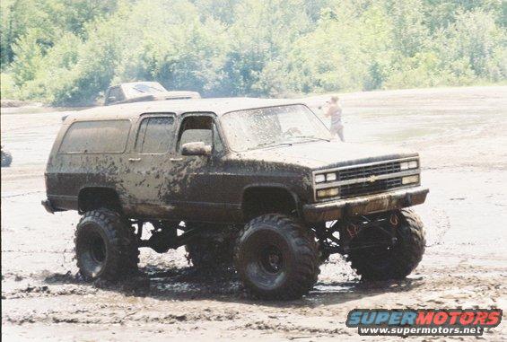 Mud-covered lifted 1991 Chevrolet Suburban in a muddy field