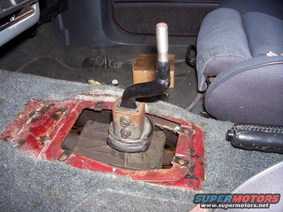 Manual transmission shifter assembly removed from vehicle floor, showing linkage and mounting points