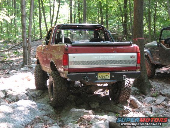 Red Ford Bronco with lifted suspension and off-road tires on rocky terrain