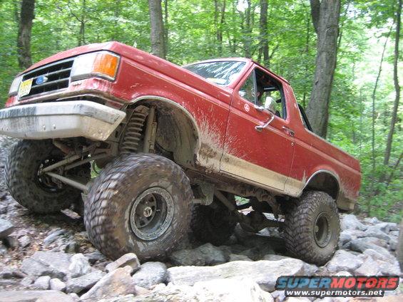 red SUV with big tires on rocky trail