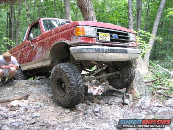 Red 1990 Ford Bronco navigating rocky terrain
