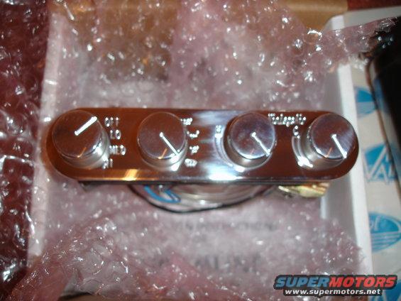 Chrome air conditioning control panel with four knobs and labels like OFF, LO, MED, HI