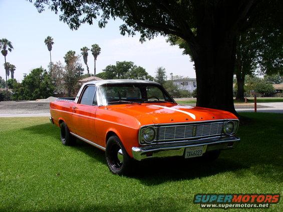 Orange 1966 Ford Ranchero with a white stripe on the hood, parked on grass under a tree