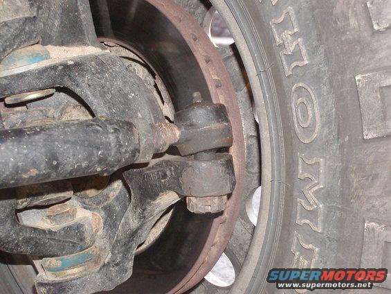 Close-up of a vehicle's steering linkage, tie rod end, brake rotor, and tire tread