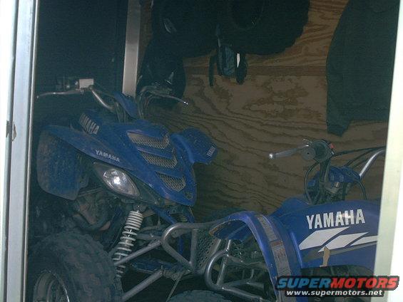 Blue Yamaha ATV parked inside a trailer, front quarter view