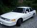 1994 Ford Crown Victoria - This white sedan, likely a 1992 model, is viewed from the front three-quarter angle on a gravel surface.