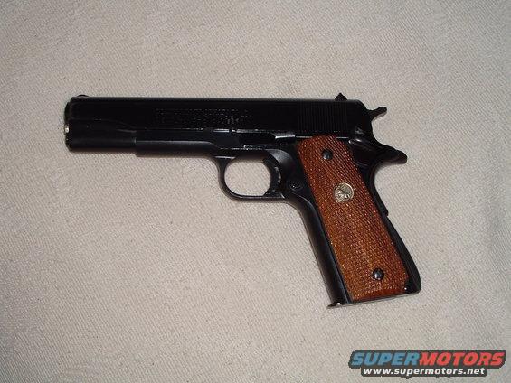 Black pistol with wood grips, side view. Supermotors.net logo at bottom right