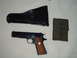 1995 Mercury Grand Marquis - A Colt M1911 pistol is displayed with its holster and a magazine pouch, all marked with US insignia.