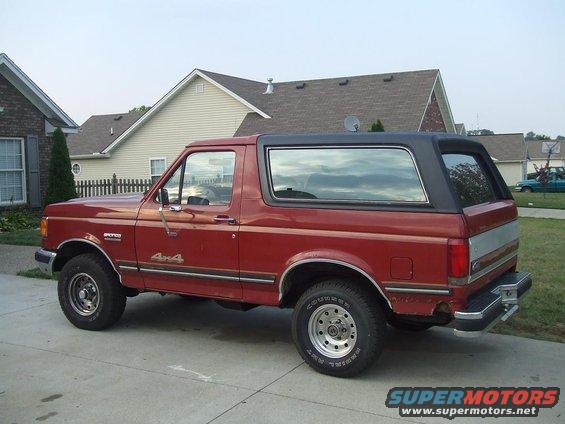 Red 1987 Ford Bronco 4x4 parked in driveway, side view