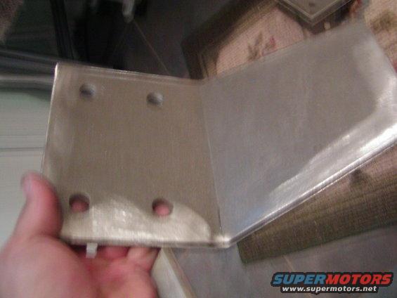 Metal bracket with four holes, held by a hand