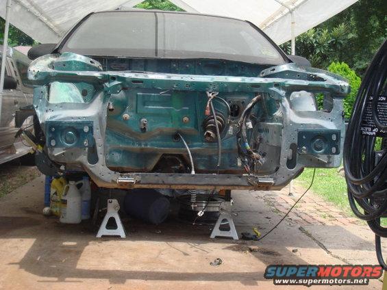 1993 Ford Taurus front end disassembled on jack stands, showing engine bay structure