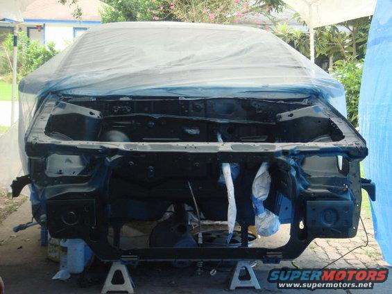 car front end disassembled on jack stands, covered with plastic sheeting