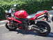 2007 Yamaha R1 - A red 2007 Yamaha R1 motorcycle is parked on pavement with a hedge in the background.