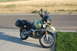 1998 BMW R1100GS ABS - A green 1998 BMW R1100GS ABS motorcycle with black saddlebags is parked on a sidewalk next to a road.