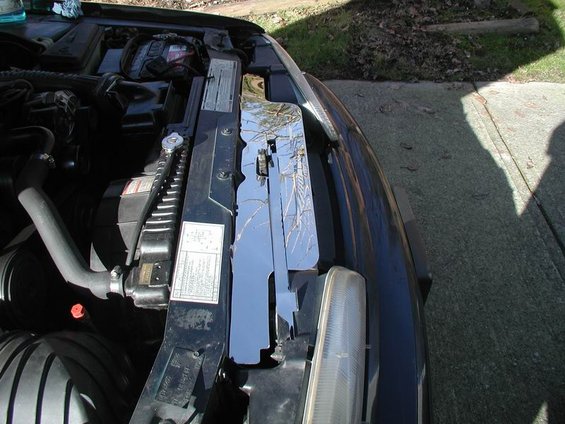 Car engine bay with radiator and a shiny chrome piece near the headlight